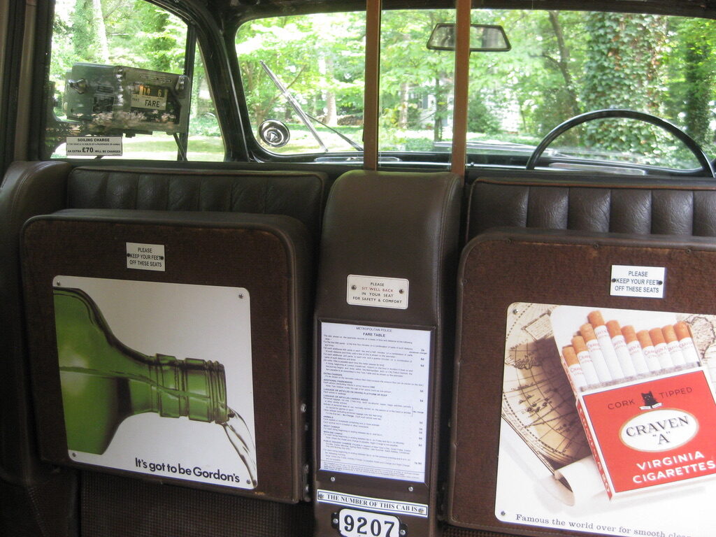 The folding jump seats with period advertisement panels either side of the Metropolitan Police fare table, and the cab number 9207 below.